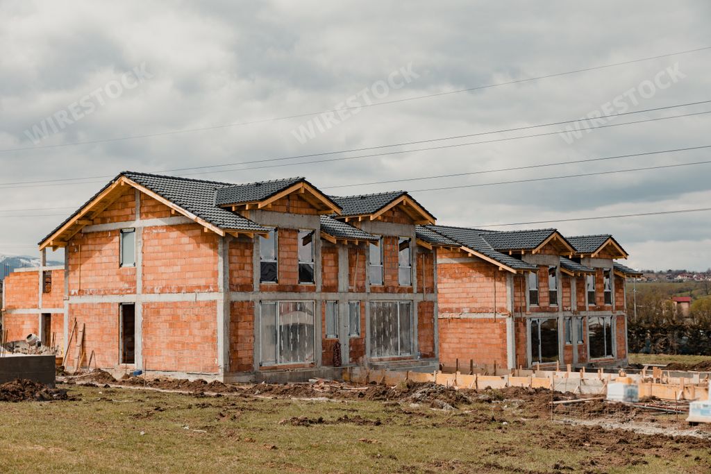 the newly built orange houses with black roofs under a cloudy sky - construction