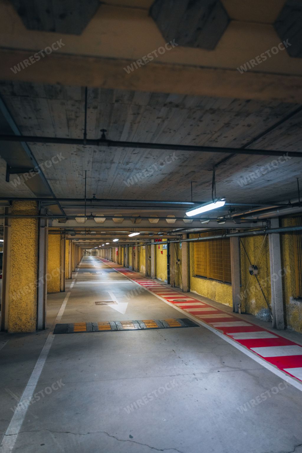 A vertical shot of a parking deck with arrows, speed bump, and signs