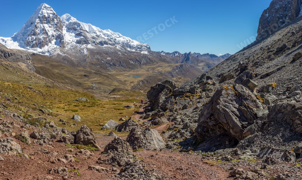 A landscape shot of a beautiful valley surrounded by huge mountains with snowy peaks. Perfect for a wallpaper or a background.