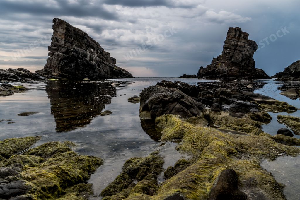 The beautiful rock formations covered with moss at Bulgaria Beach against a cloudy sky