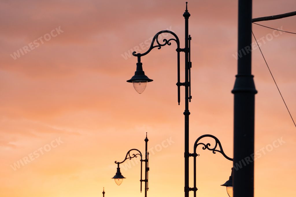 A low angle shot of old street lamps under sunset sky