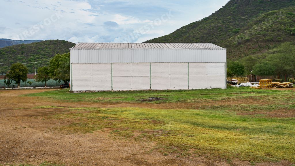 warehouse to store and manufacture products, within a field near a hill with a very beautiful sky