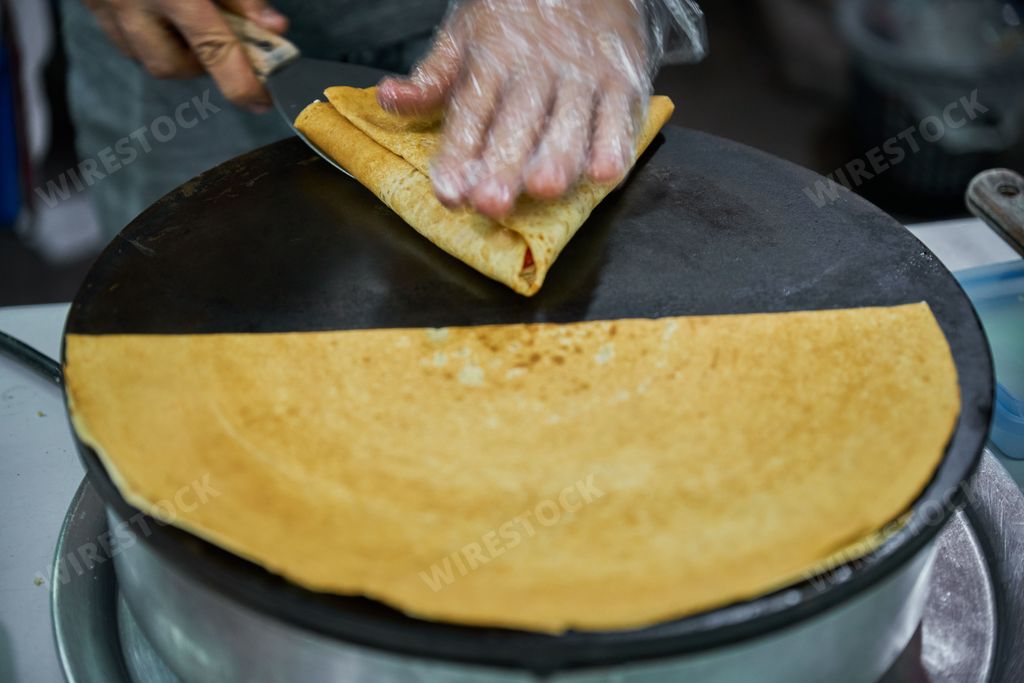 Making delicious crepes on a grill with fruit and chocolate