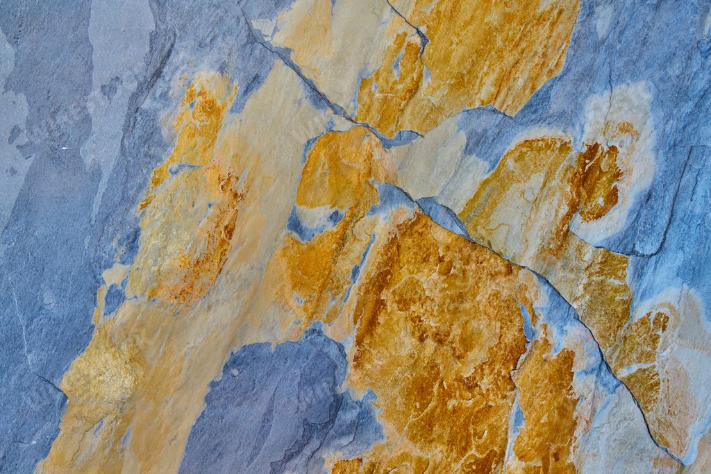 Rough stone texture with rust in blue and yellow colors with orange placed on a wall on a facade