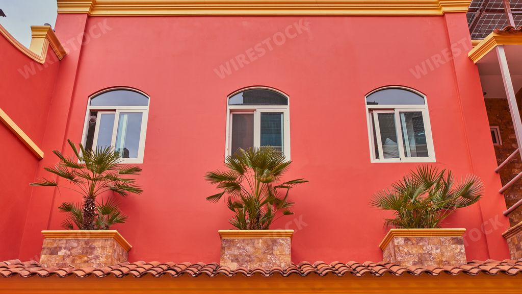 Salmon-colored hotel facade with symmetrical windows and balconies