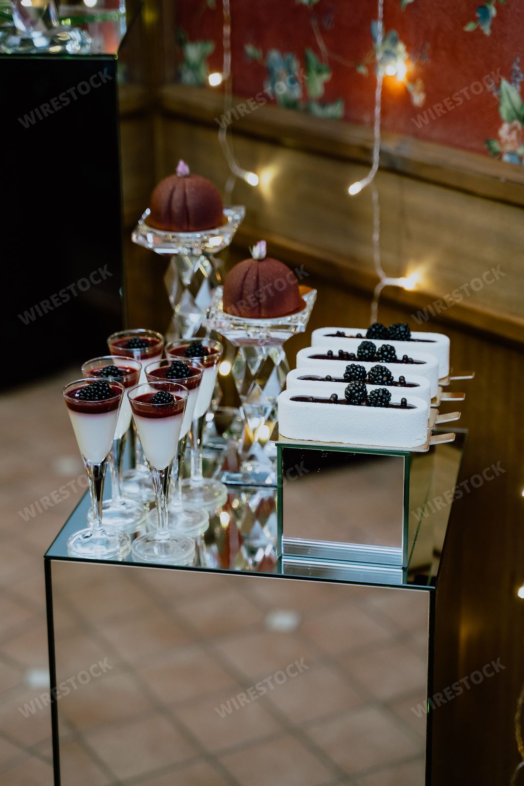 A vertical shot of a dessert corner of a decorated restaurant with sweets put on a mirror table