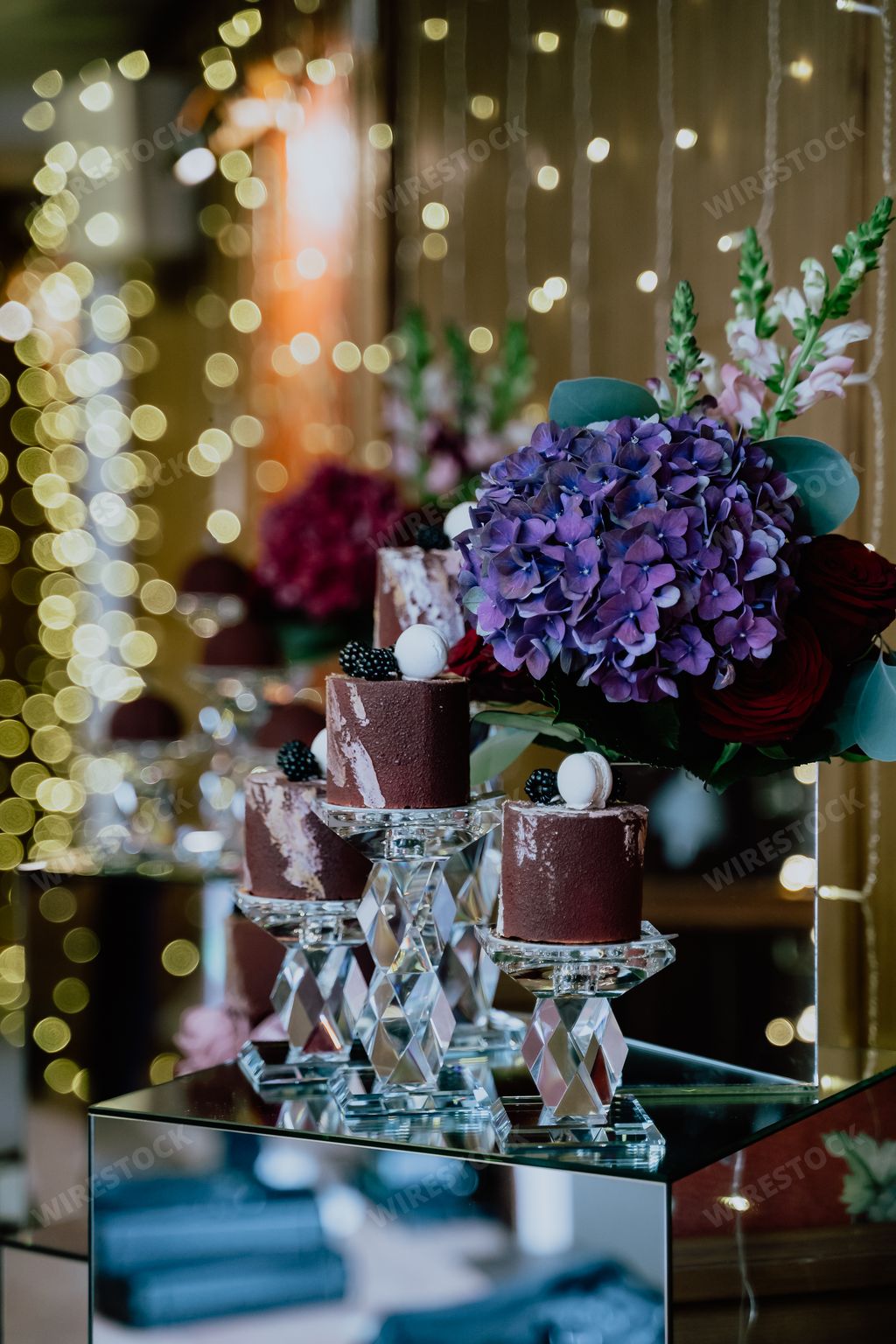 A vertical shot of a dessert corner of a restaurant with sweets and flower put on a mirror table