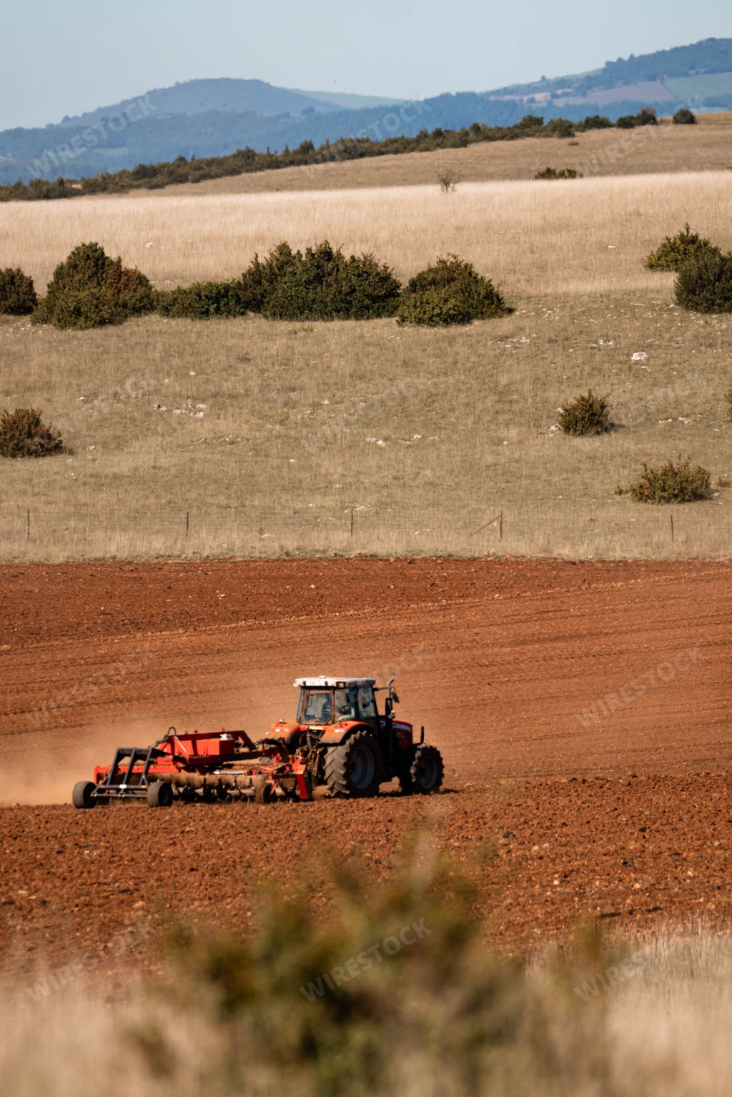 tractor ploughing red orange field