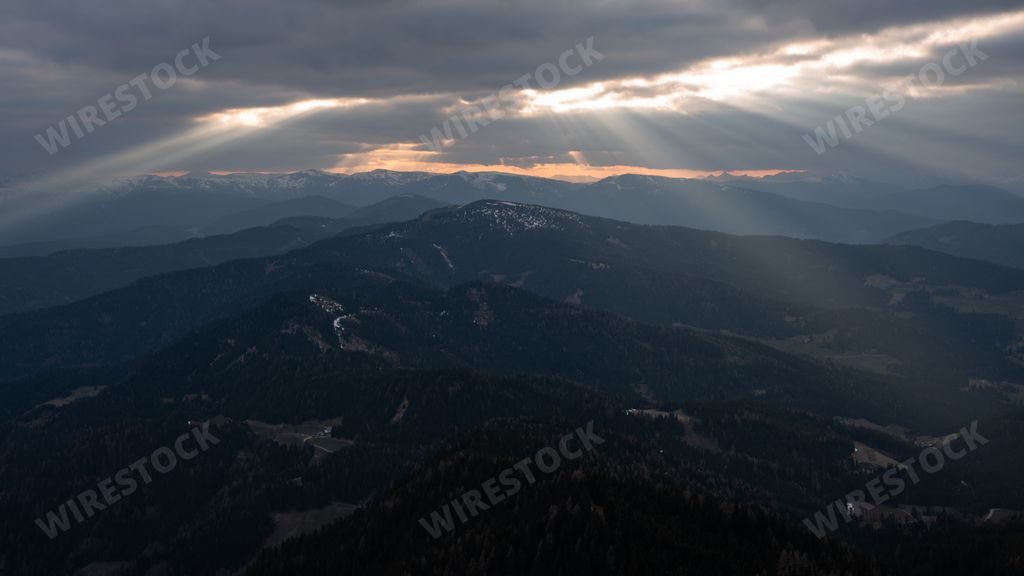 A scenic view of beautiful snowy mountains against a cloudy sky and sunlight