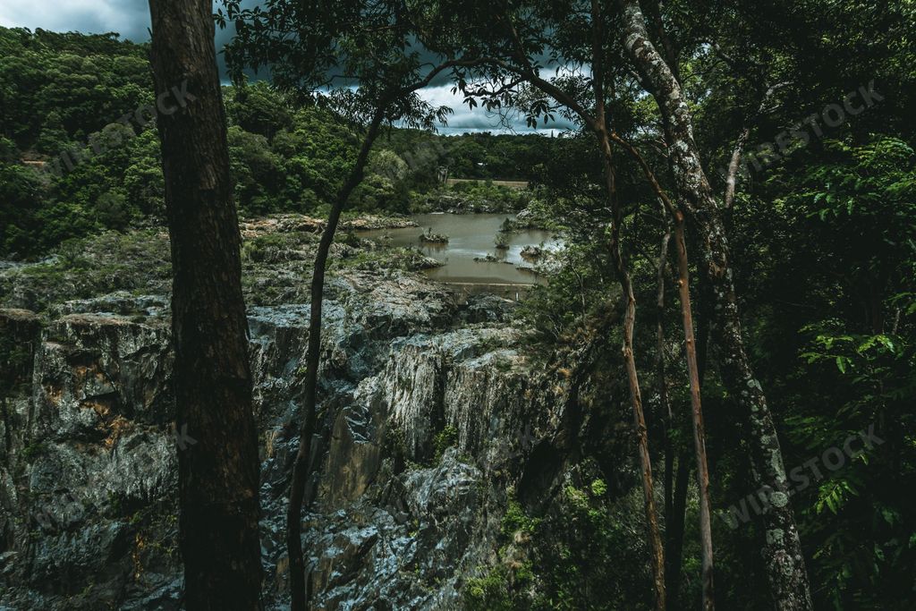A breathtaking scenery of a river on a big rock formation in the middle of a forest