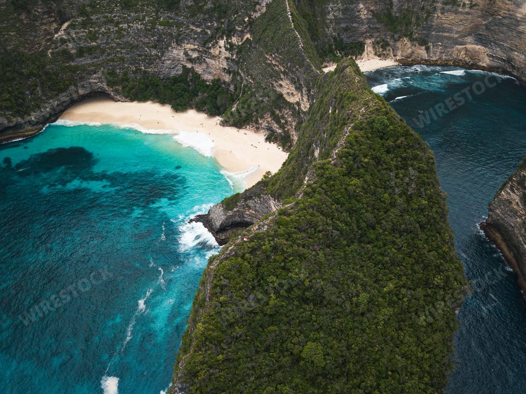 A bird's eye view of the cliffs covered in greenery surrounded by the sea at daytime - perfect for wallpapers