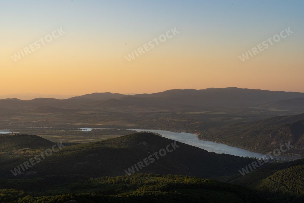 A mesmerizing view of a landscape surrounded by mountains gleaming under the sunset
