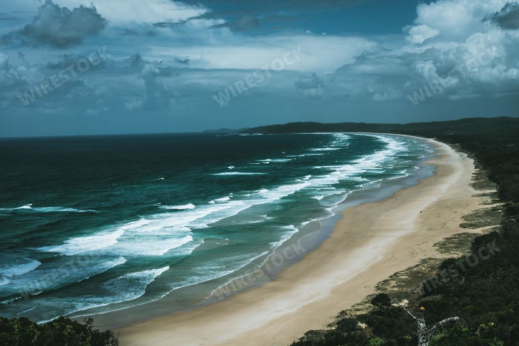A beautiful scenery of a beach in front of a green forest during evening time