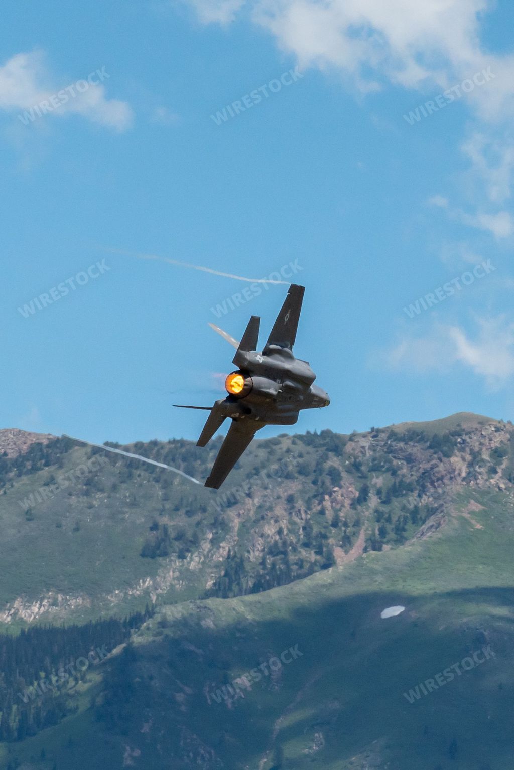 A vertical shot of an air force F-35 from a demonstration team performing aerobatics at Hill AFB against Wasatch Mountains