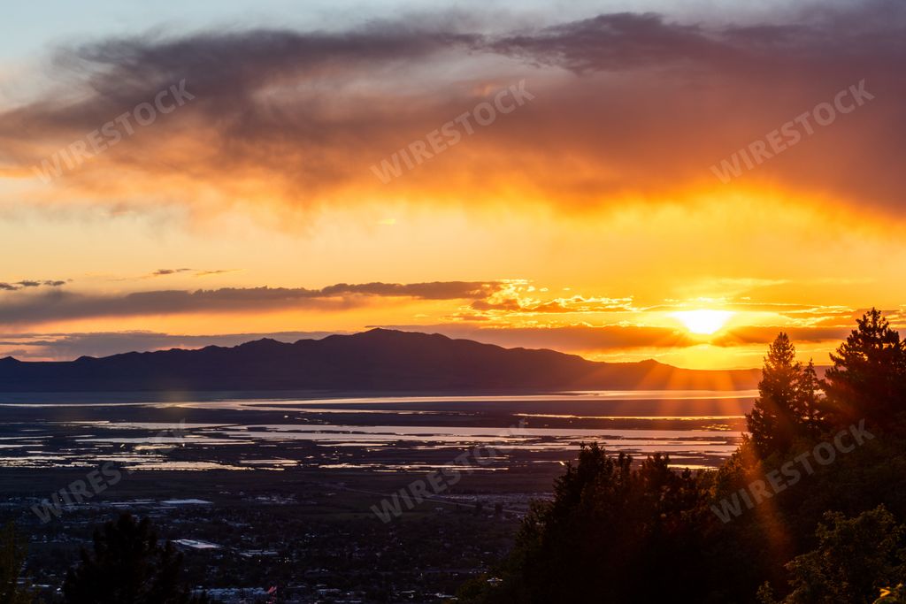 A bright sunset with the silhouette of Antelope Island, located in the Great Salt Lake, in the background