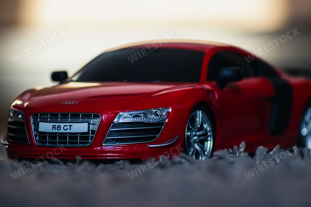 A closeup of a small Red Audi R8 toy car model on a blurred background