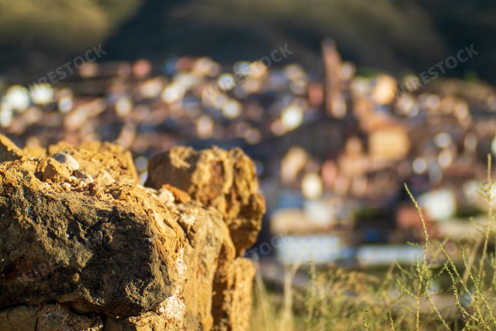 A closeup shot of golden rubble rocks with a blurry defocused town landscape for background