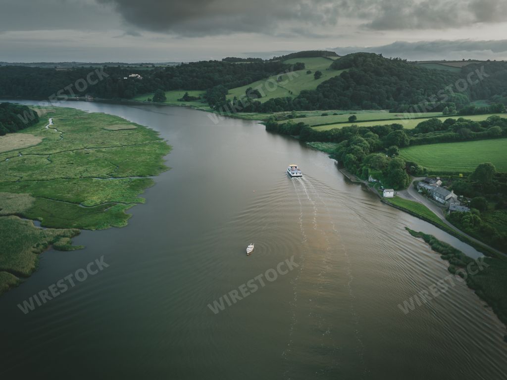 An aerial shot of a calm river surrounded by green nature and hills