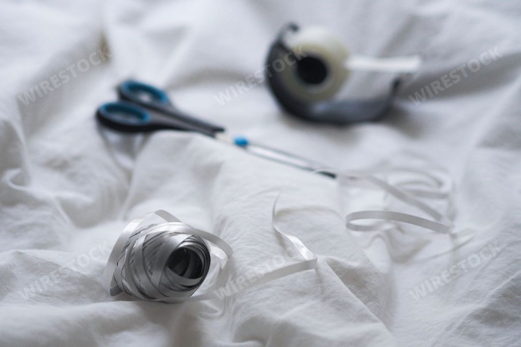 A close-up shot of a pair of scissors sitting next to a roll of adhesive tape