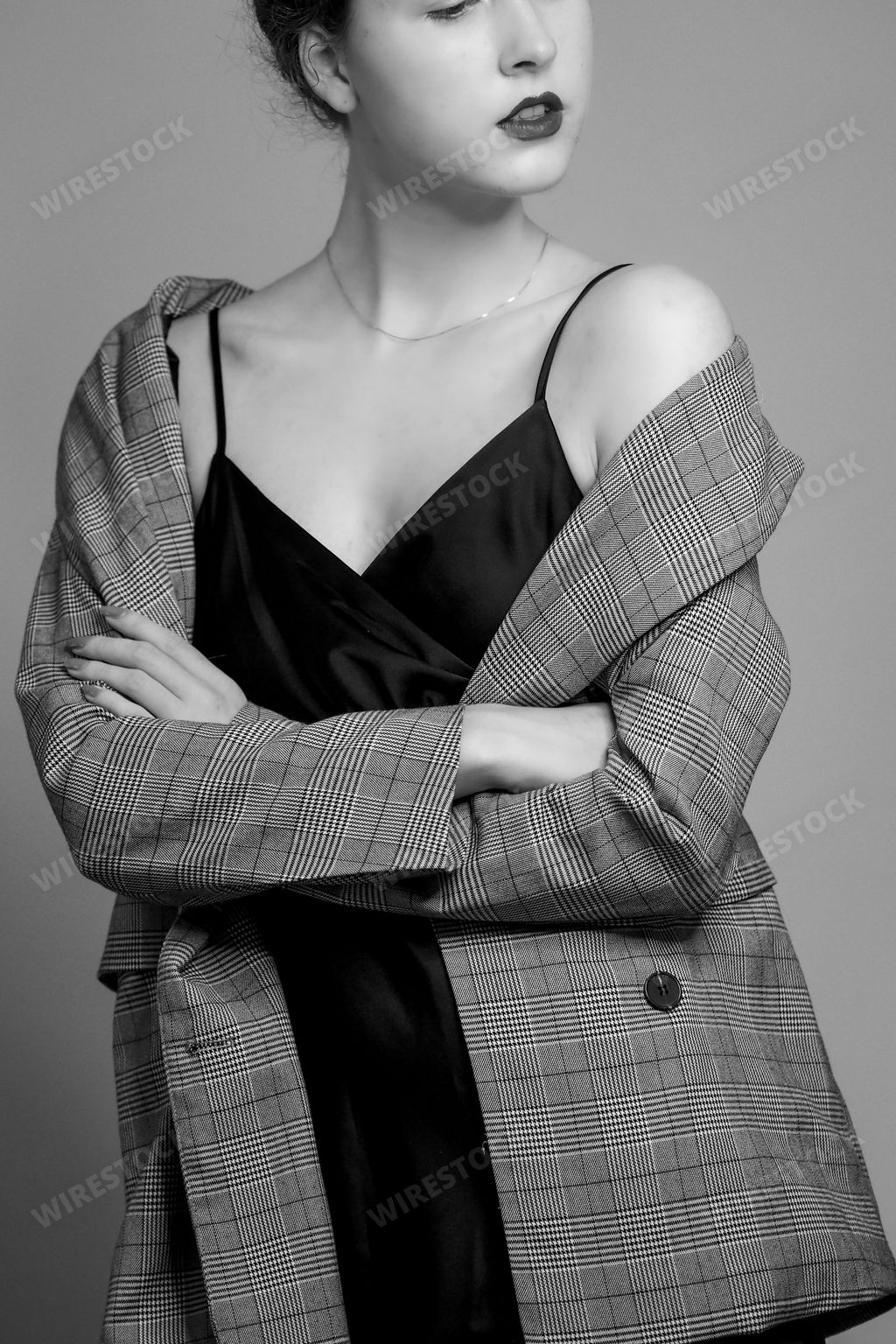 A vertical grayscale shot of an elegant female posing in a slip dress and a blazer