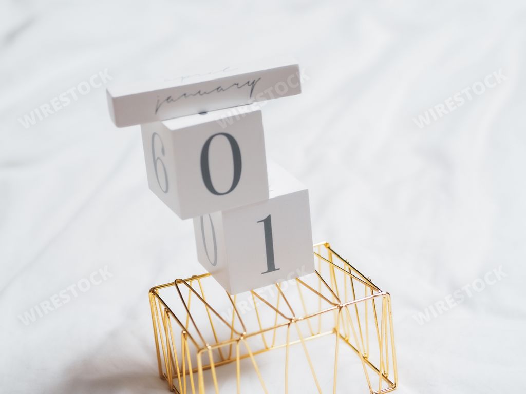 A closeup shot of calendar cubes on top of the golden metallic shape on white sheets