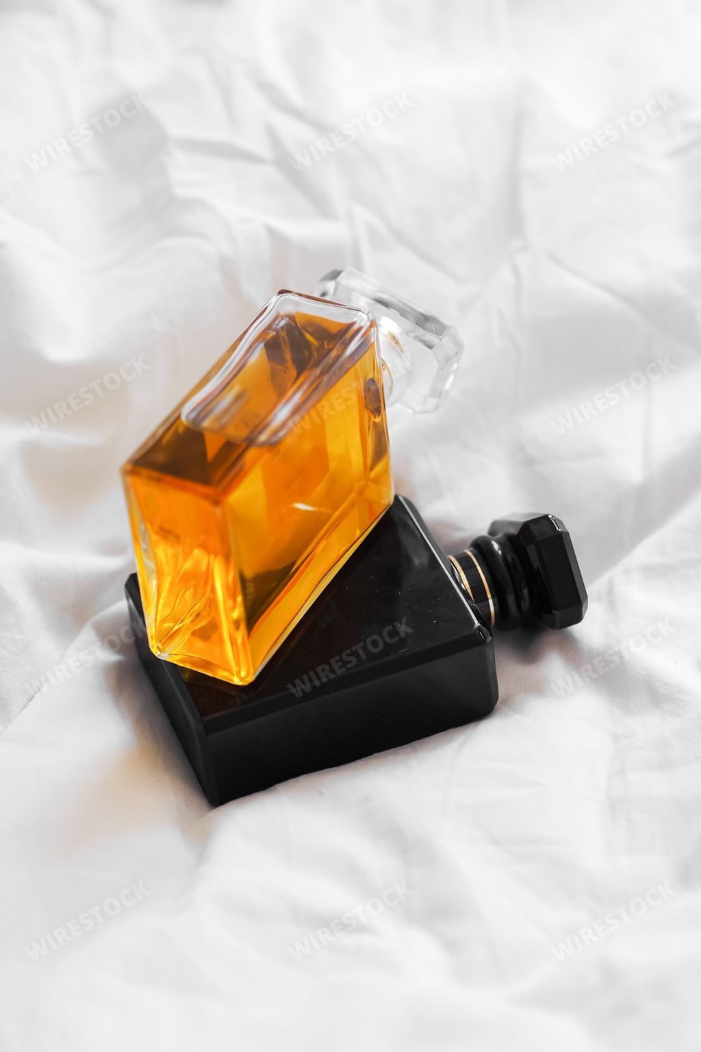 A vertical shot of two perfume bottles on a white bedsheet