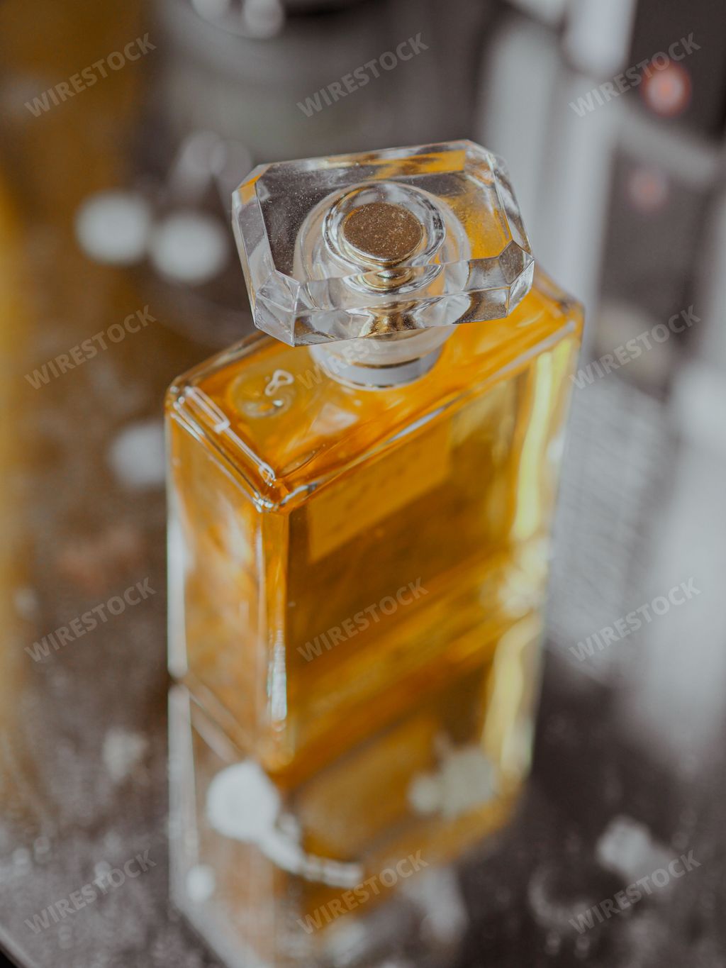 A high angle vertical shot of an aesthetic clear perfume bottle with gold substance