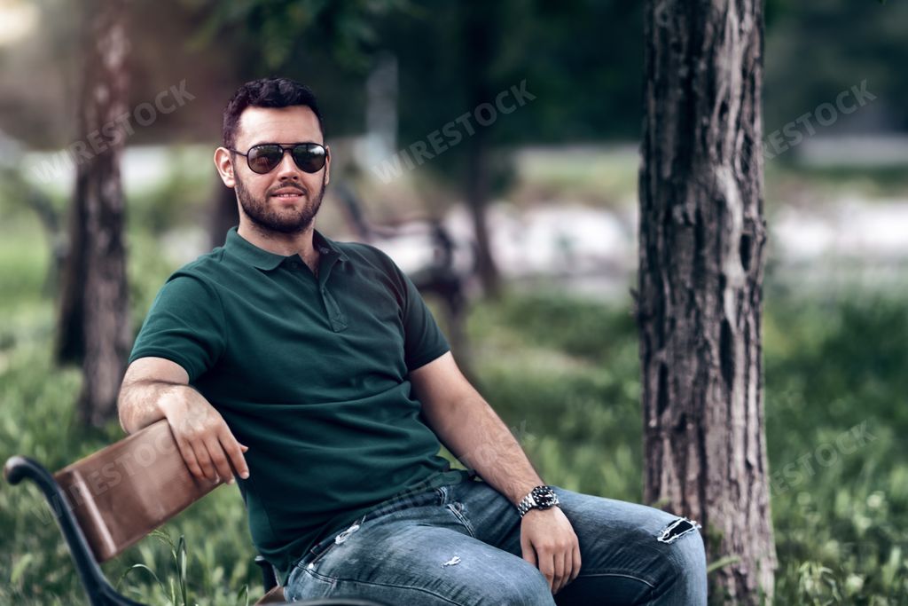A handsome caucasian male model with glasses posing n the park
