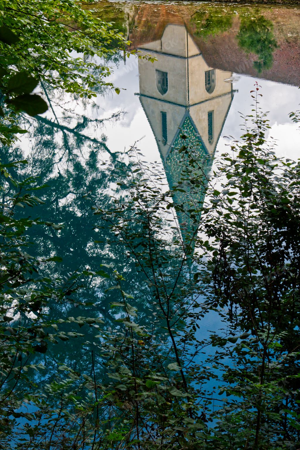 A vertical shot of a building reflected in a lake in Blautopf, Blaubeuren, Germany