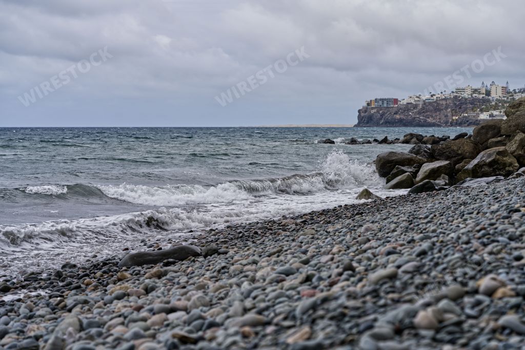A scenic view of a rocky shoreline with large waves crashing onto the rocks