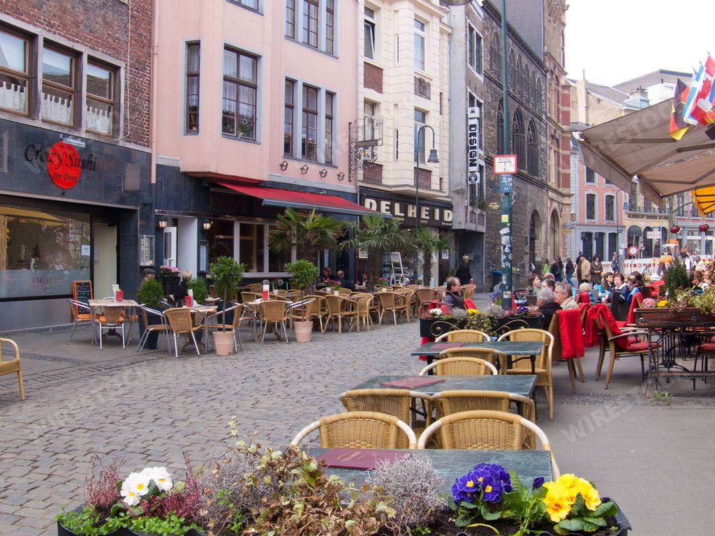 The city of Aachen in Germany with outdoor cafes and people walking around old residential buildings