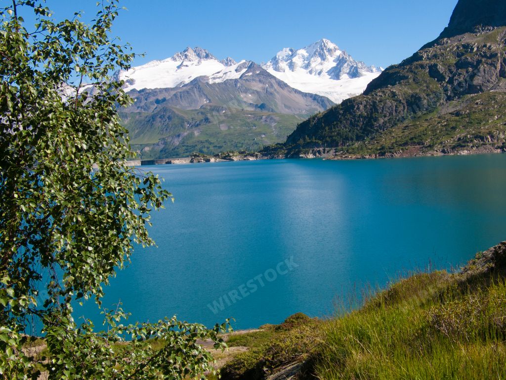 A bright summer day in the Emosson Dam, Switzerland with the water surrounded by snowy mountains