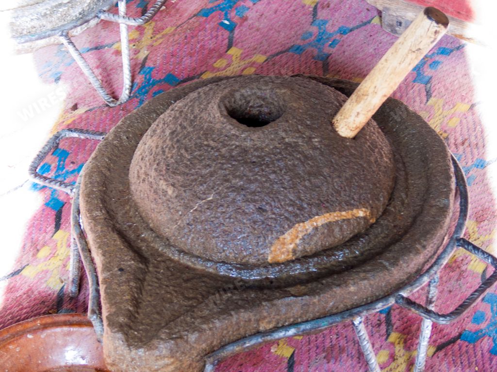 A closeup of a Millstone with a wooden handle
