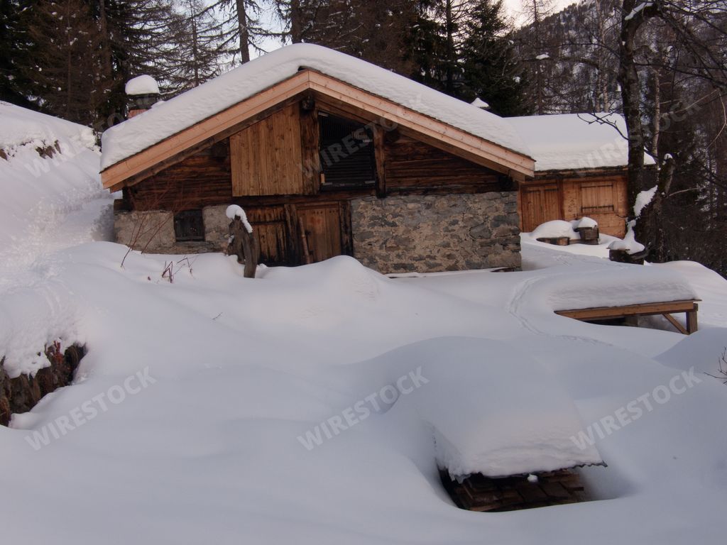 A beautiful shot of an old wooden house and the snow on roof in the forest in France