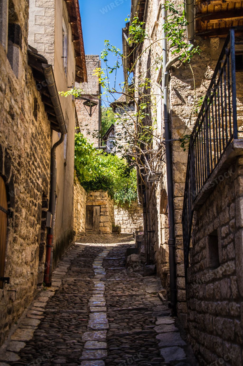 A vertical shot of a narrow street between old stone houses in Sainte-Enimie, Lozere, France, Europe