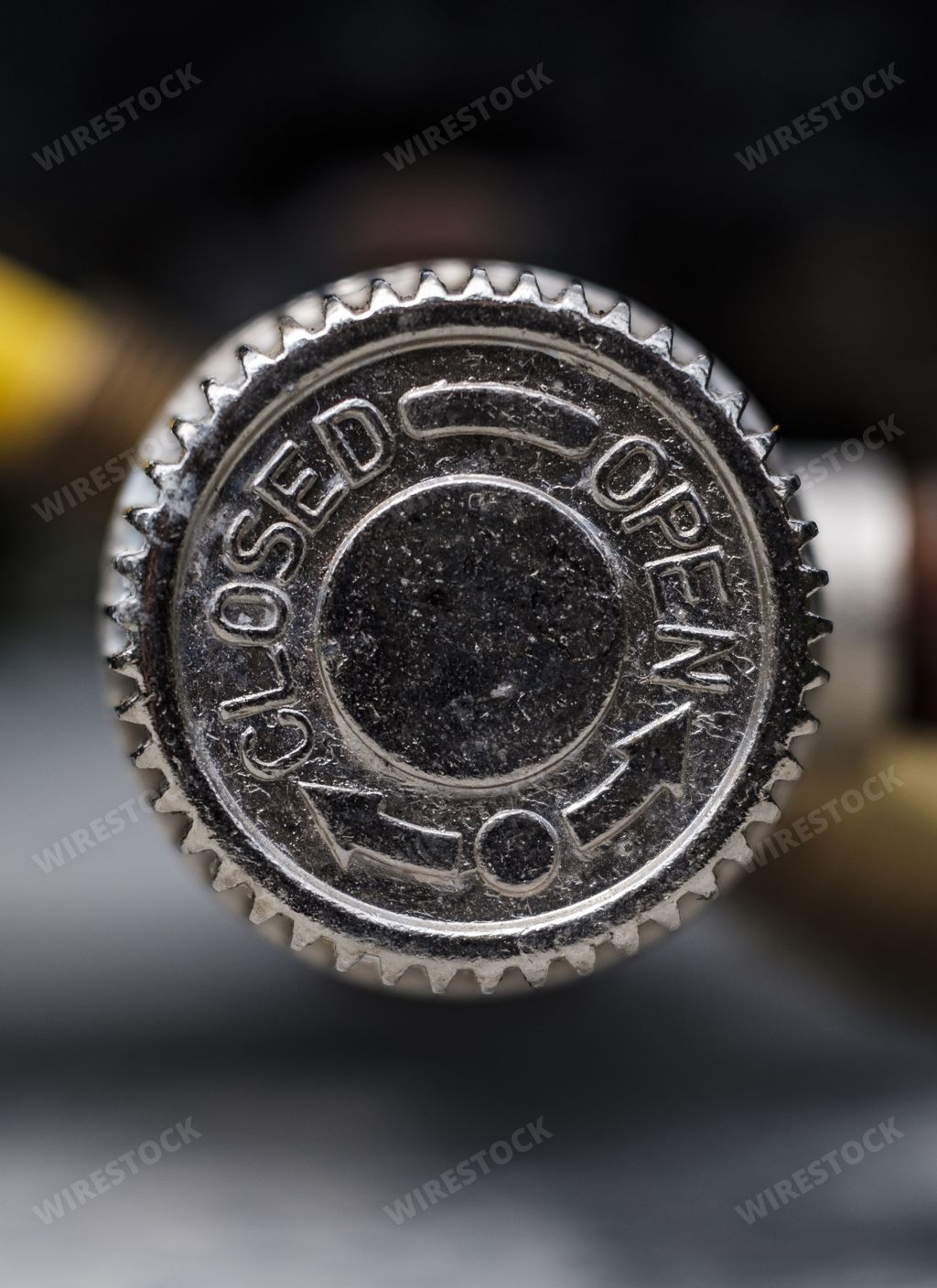A closeup of a beer bottle metal cap with arrows and writing "closed" and "open" on it with a blurred background
