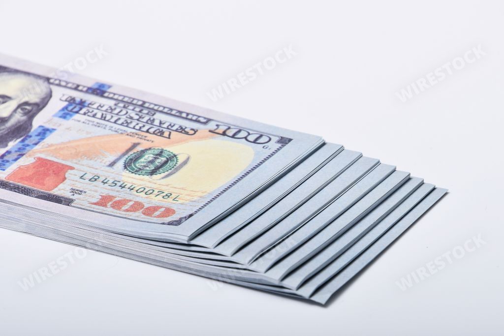 A closeup of a stack of American hundred dollars on a white table