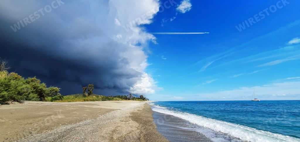 A stunning image of a sky filled with dark, ominous clouds, while the beach below is dotted with shallow pools of water