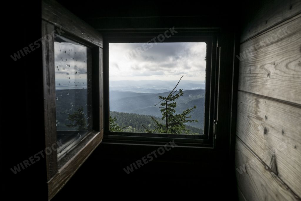 A beautiful view of the mountains from a window of a wooden house on top of a hill