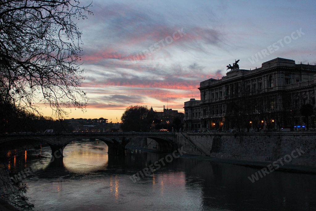 A scenic view of an arcade bridge on Tiber River in Rome, Italy at pink sunset
