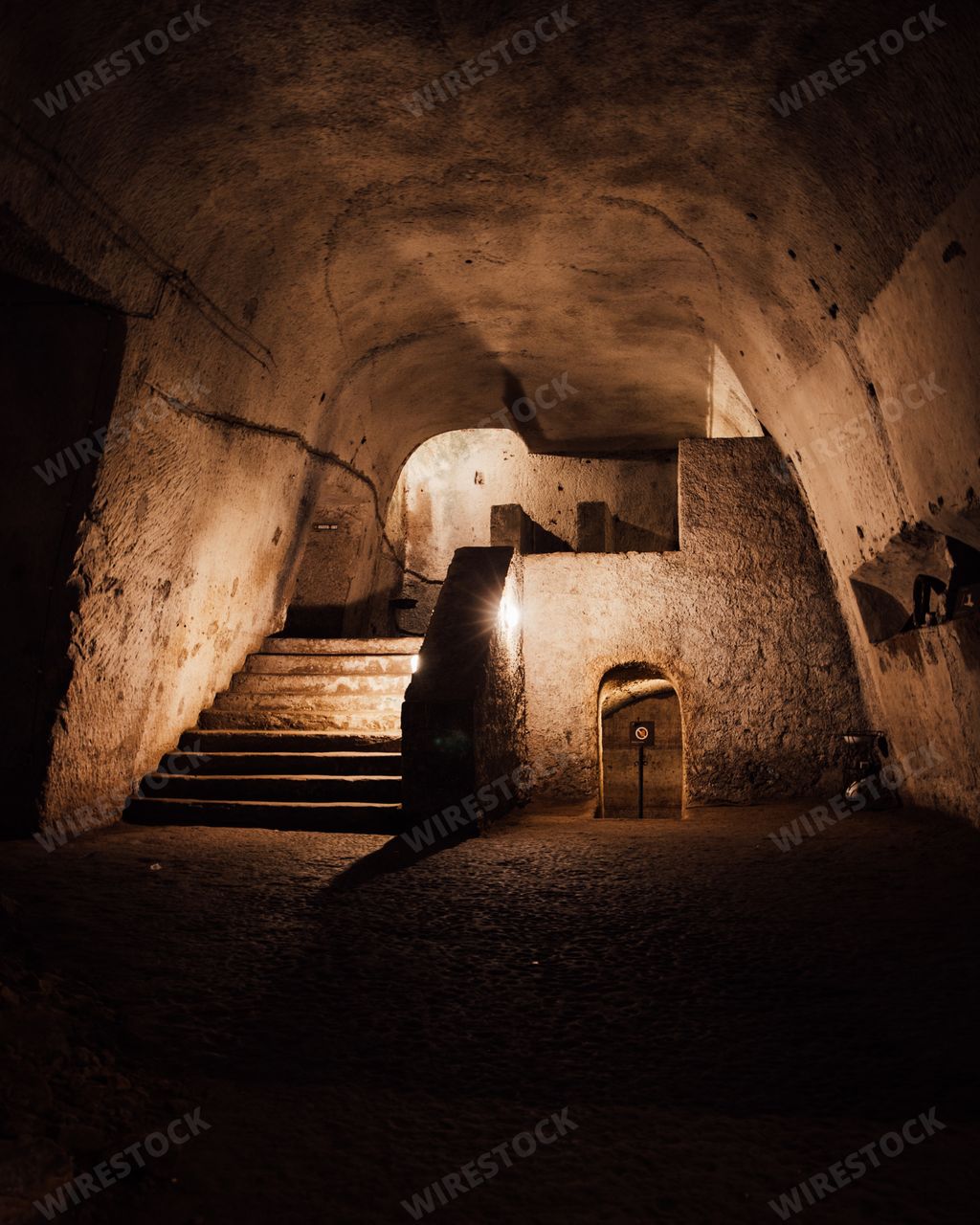 A view of a an underground hall with arched ceiling and stone walls and stairs