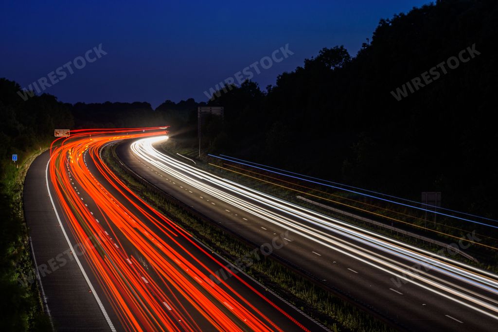 The fast moving cars on the M5 highway leave traffic light trails and light streaks as they pass along a busy motorway