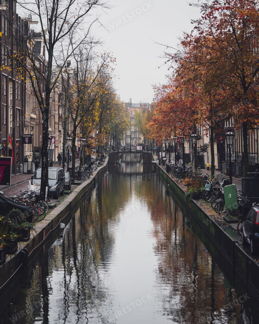 Amsterdam, Netherlands - November 27 2022: A canal running through the De Wallen red light district in Amsterdam on a misty autumn morning.
