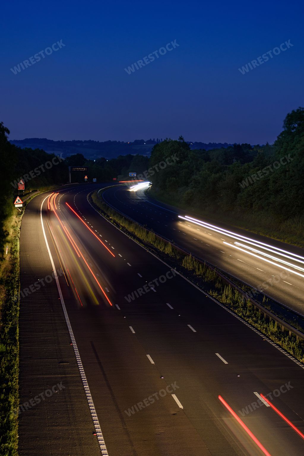 The fast moving cars on the M5 highway leave traffic light trails and light streaks as they pass along a busy motorway