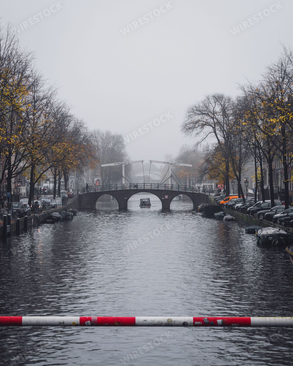 Amsterdam, Netherlands - November 27 2022: A traditional skinny bridge in Amsterdam on a foggy autumnal morning.