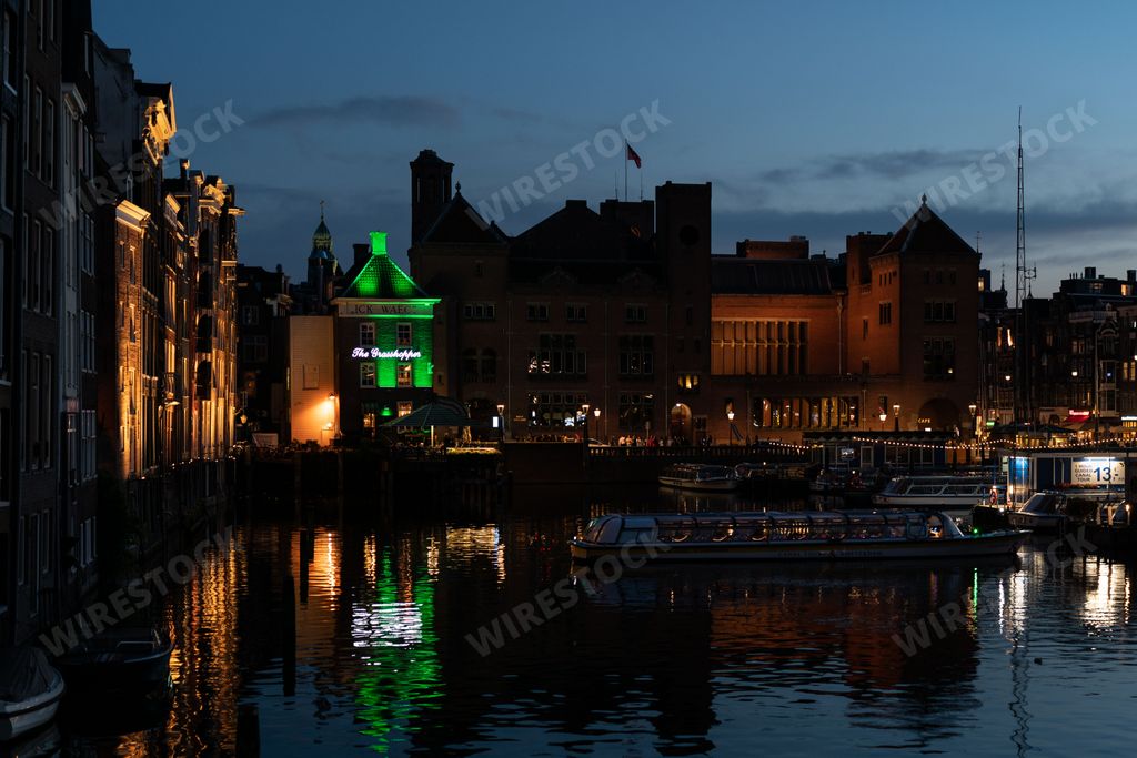 A night time view of Damrak in Amsterdam, with The Grasshopper bar lit up in the background and light slowly
