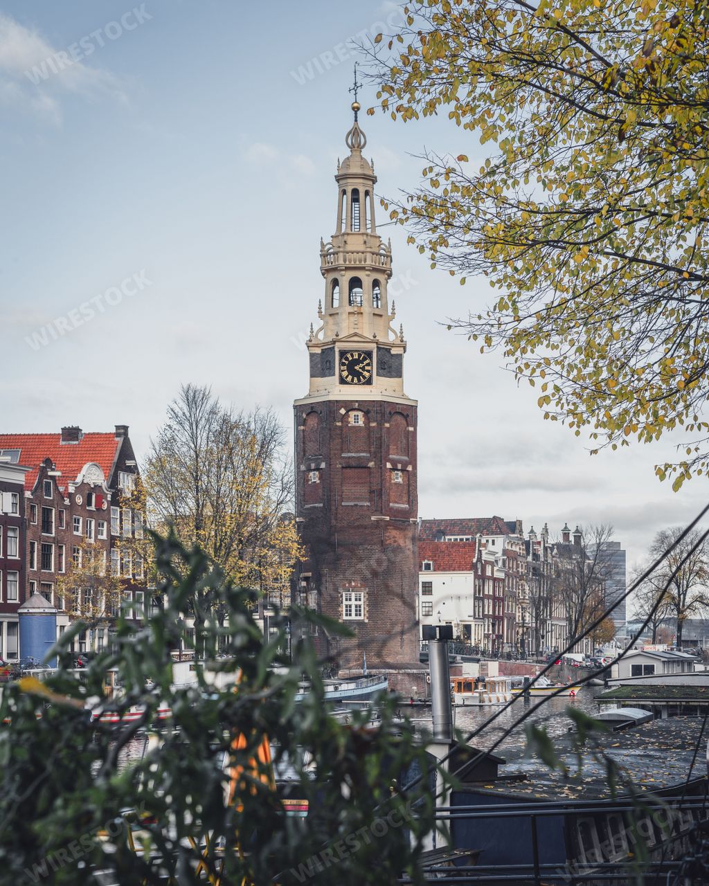 Amsterdam, Netherlands - November 28 2022: An autumn afternoon in Amsterdam, Montelbaanstoren is majestic beneath a cloudy blue sky.