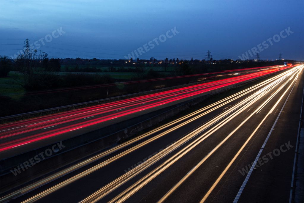 Light trails left by speeding traffic travelling through the night on the M40 motorway in the UK. Slow shutter speed and long exposure photography.