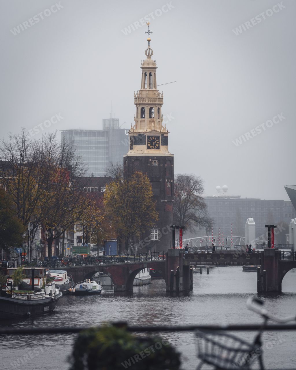 Amsterdam, Netherlands - November 27 2022: Montelbaanstoren tower, next to a canal on a grey autumn day in Amsterdam, with the famous NEMO museum.