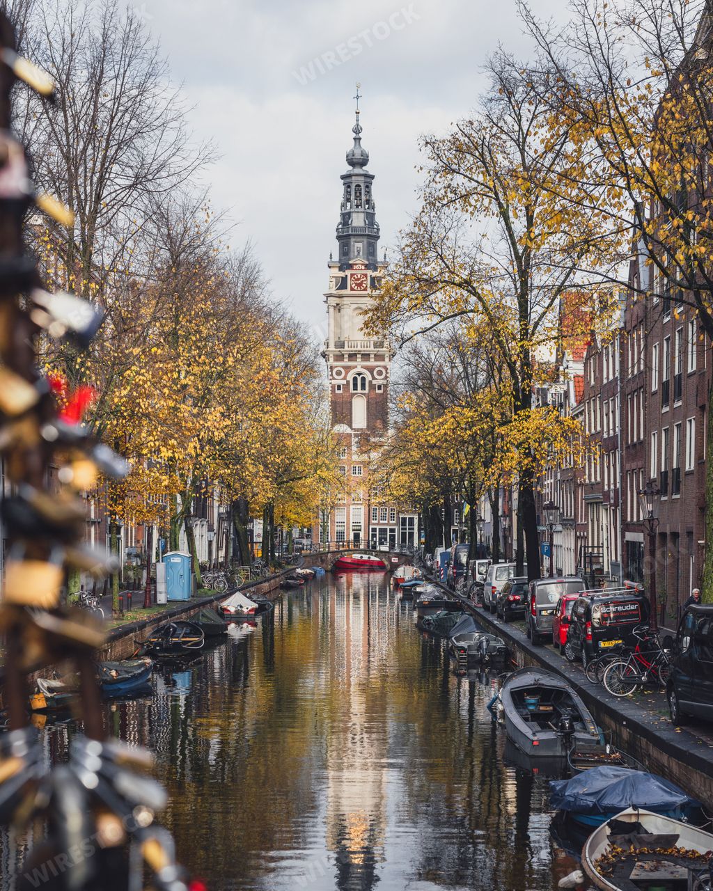 Amsterdam, Netherlands - November 27 2022: Love locks on the Staalmeesterbrug bridge, looking towards Zuiderkerk Tower in autumn.